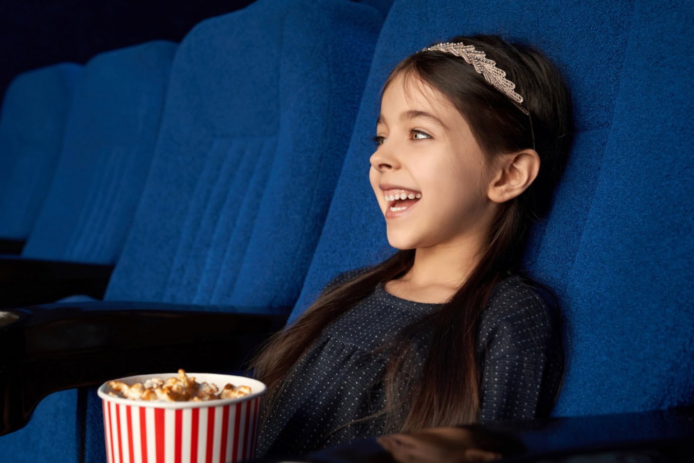 joyful little girl watching movie laughing cinema 1 scaled joyful little girl watching movie laughing cinema