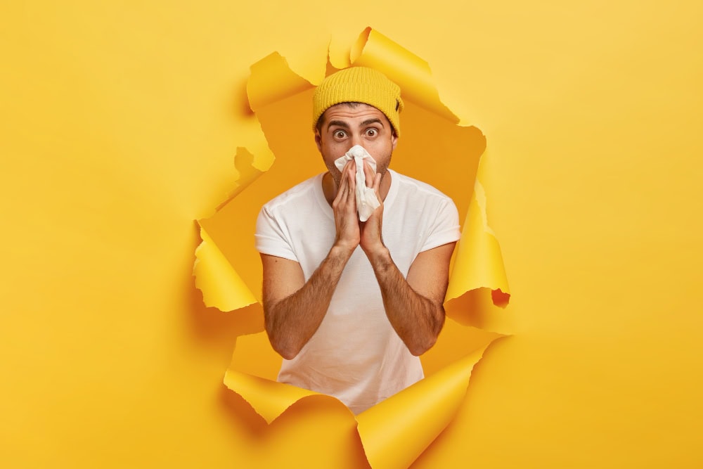 surprised young man caught cold has running nose sneezes tissue Grip