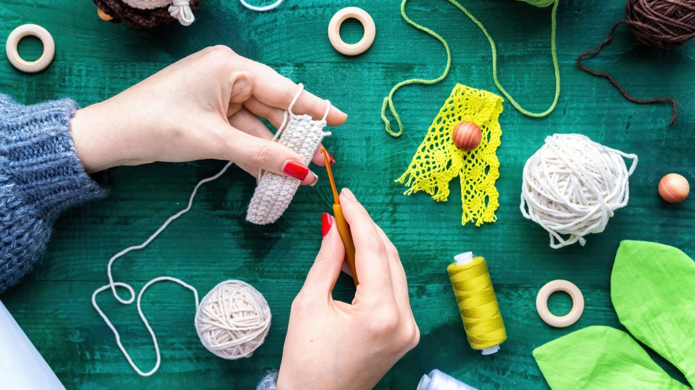 woman is knitting using hooks white yarn table with equipment scaled amigurumi